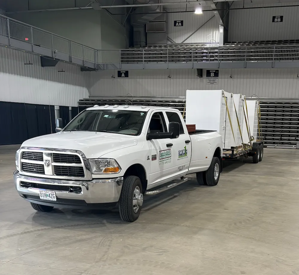 White pickup truck towing trailer inside arena
