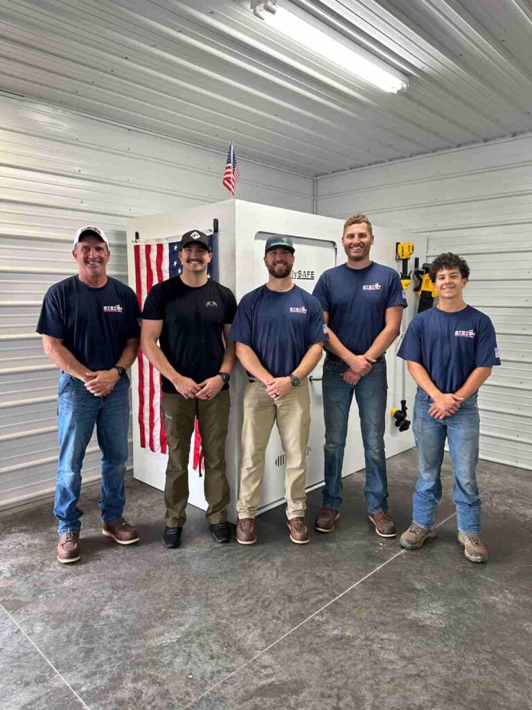 Five men standing in workshop by large safe