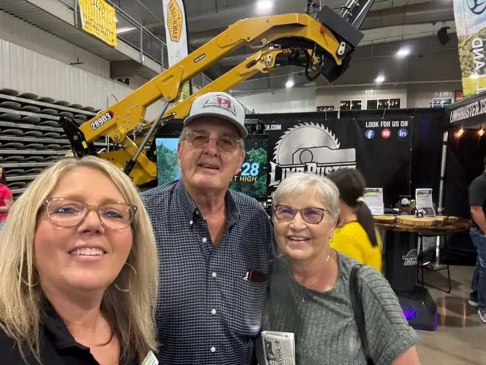 Three people posing at equipment trade show booth