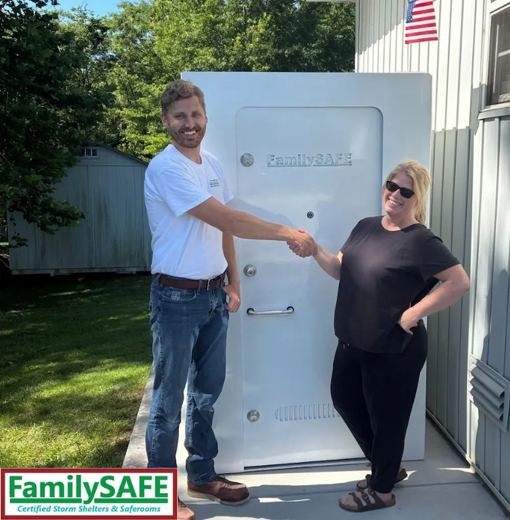 Man and woman shaking hands by storm shelter
