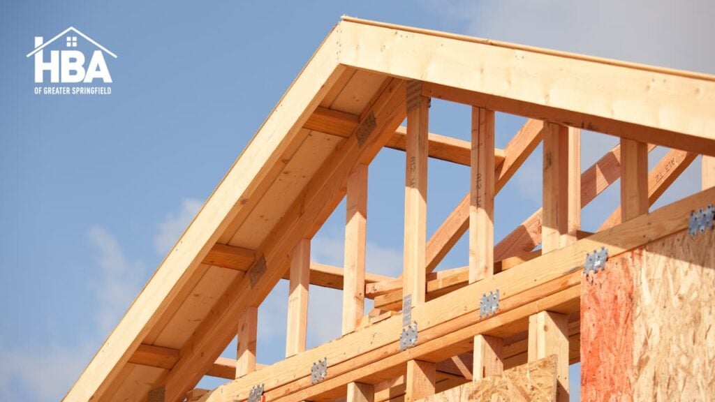 Wooden house framing under construction against blue sky
