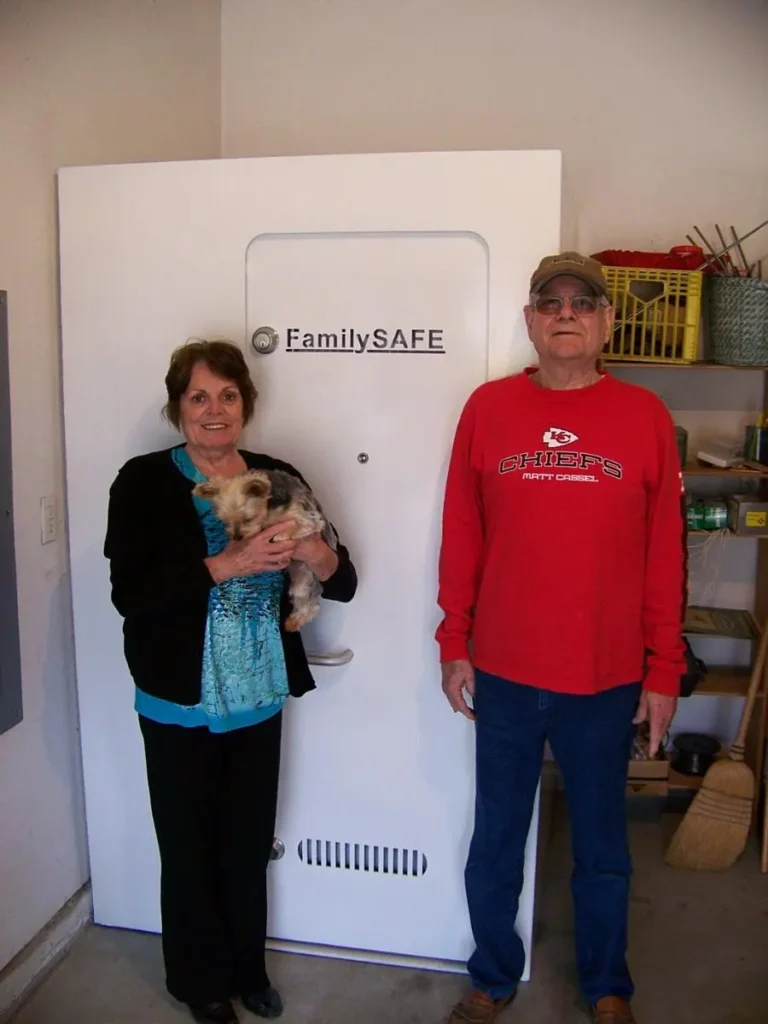 Couple with dog standing beside large safe door