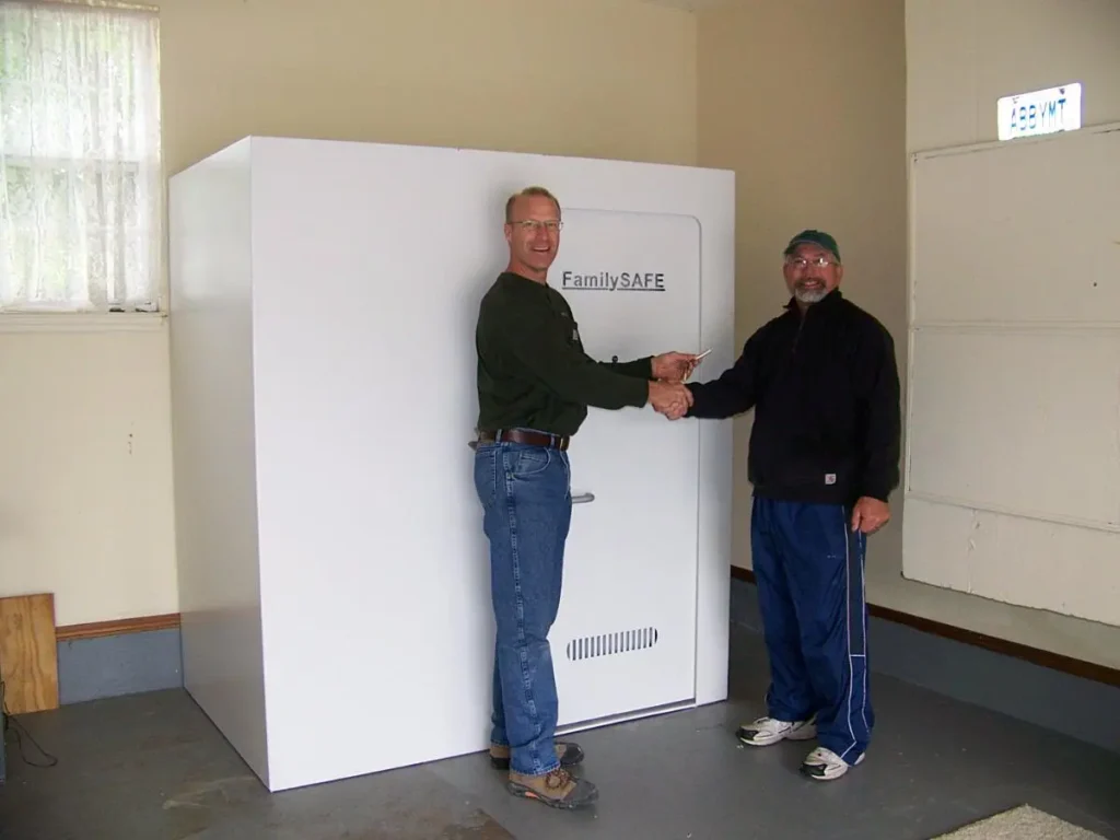 Two men shaking hands beside large FamilySAFE vault