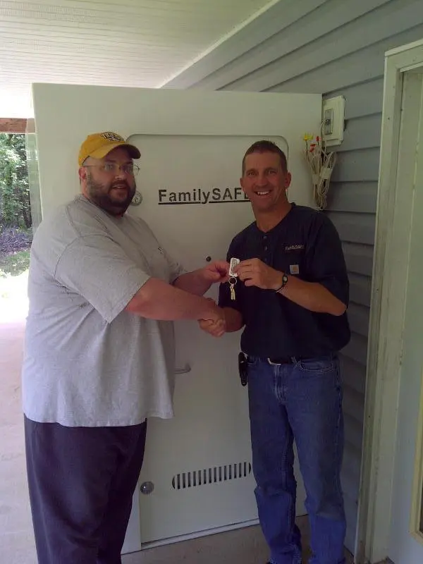 Two men exchanging keys beside large safe