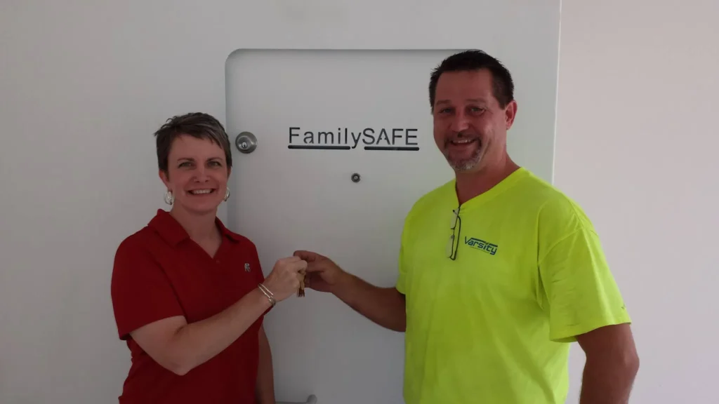 Two people exchanging keys in front of FamilySAFE door