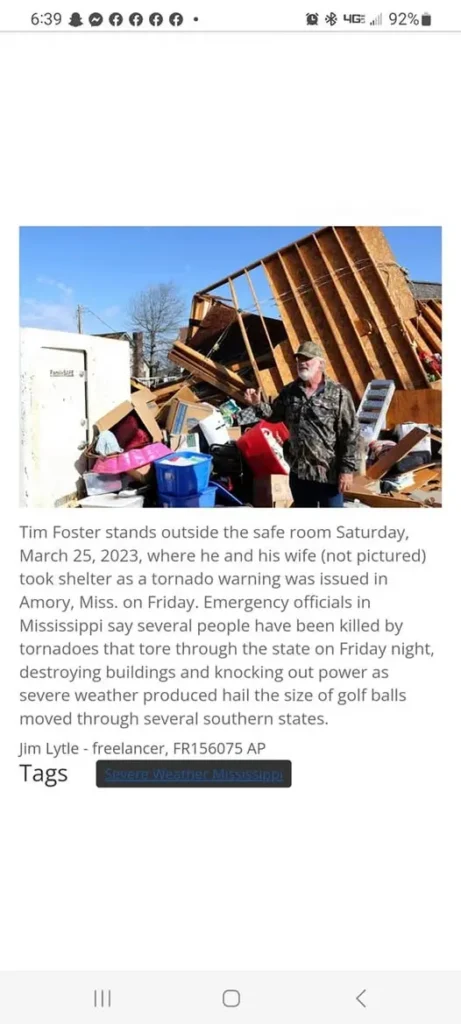 Man stands amid tornado-damaged debris outside safe room