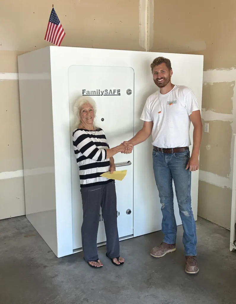 Woman and installer shaking hands by large storm shelter