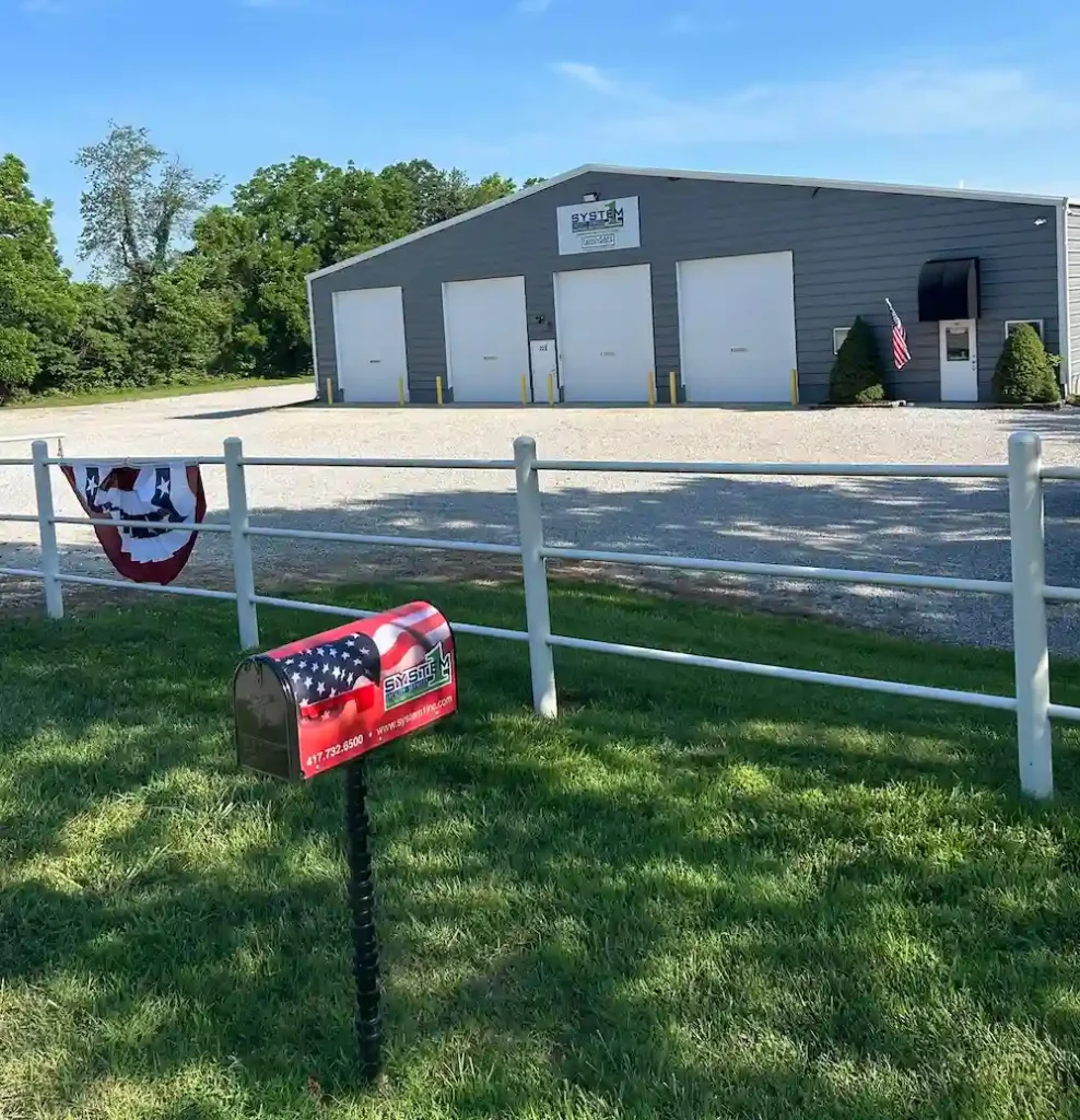 Gray industrial building with patriotic mailbox and fence