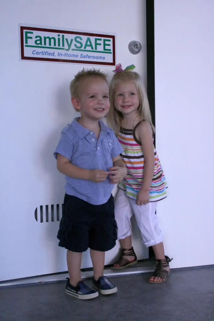 Two children smiling by FamilySAFE saferoom door