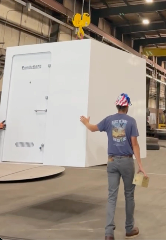 Person guiding large white safe in factory
