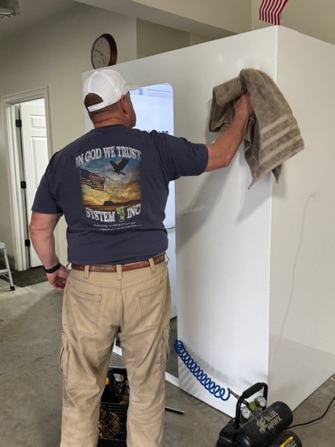 Man cleaning white refrigerator in garage