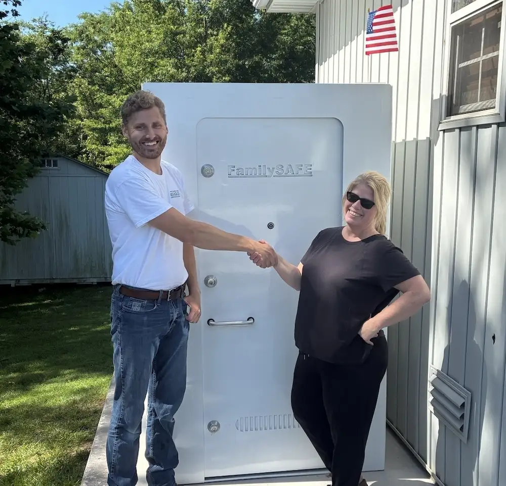 Two people shaking hands beside storm shelter door