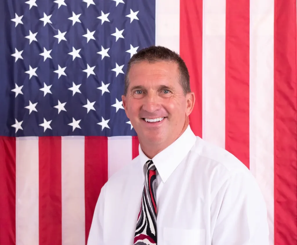 Man in tie smiling before American flag