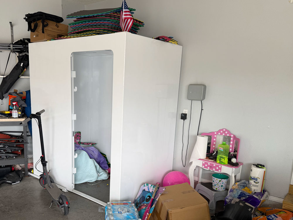 White enclosed booth in cluttered garage with scooter